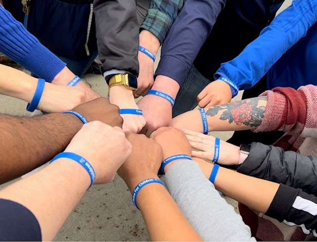 Group of hands with blue awareness bracelets