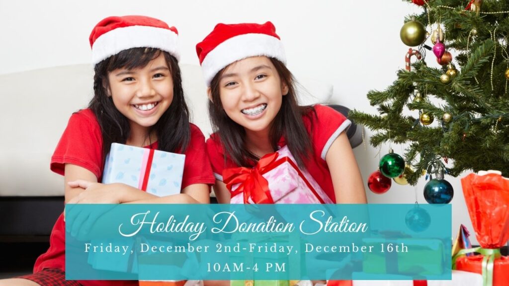 two girls dressed in holiday apparel hugging presents with wording that says Holiday Donation Station. Friday December 2nd-Friday December 16th 10 AM-4 PM