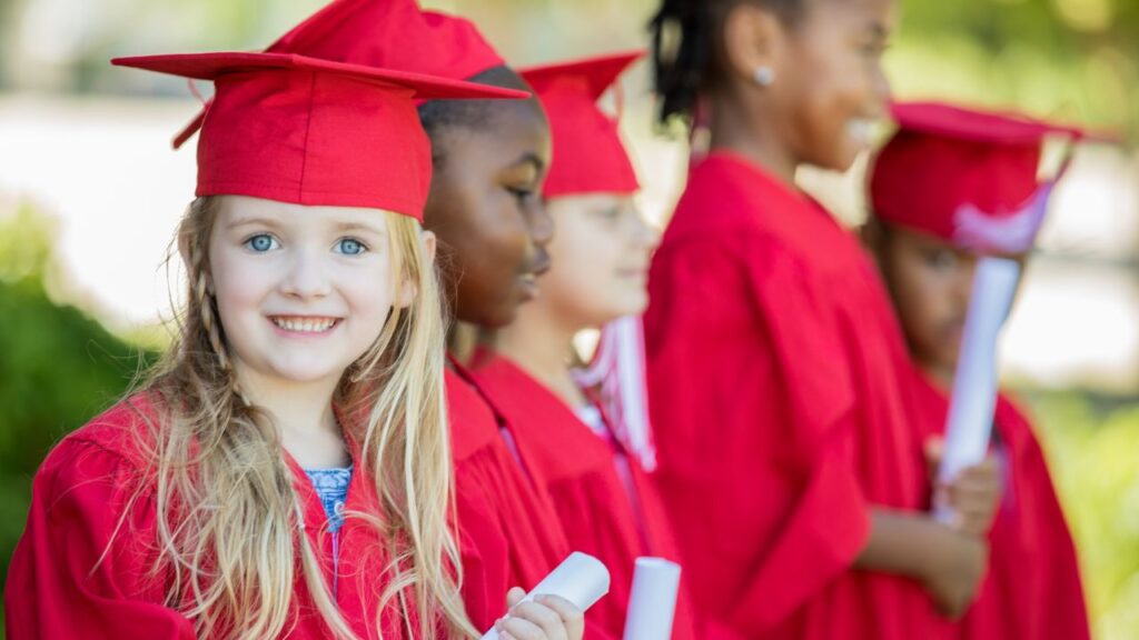 Girl holding a diploma graduating from preschool