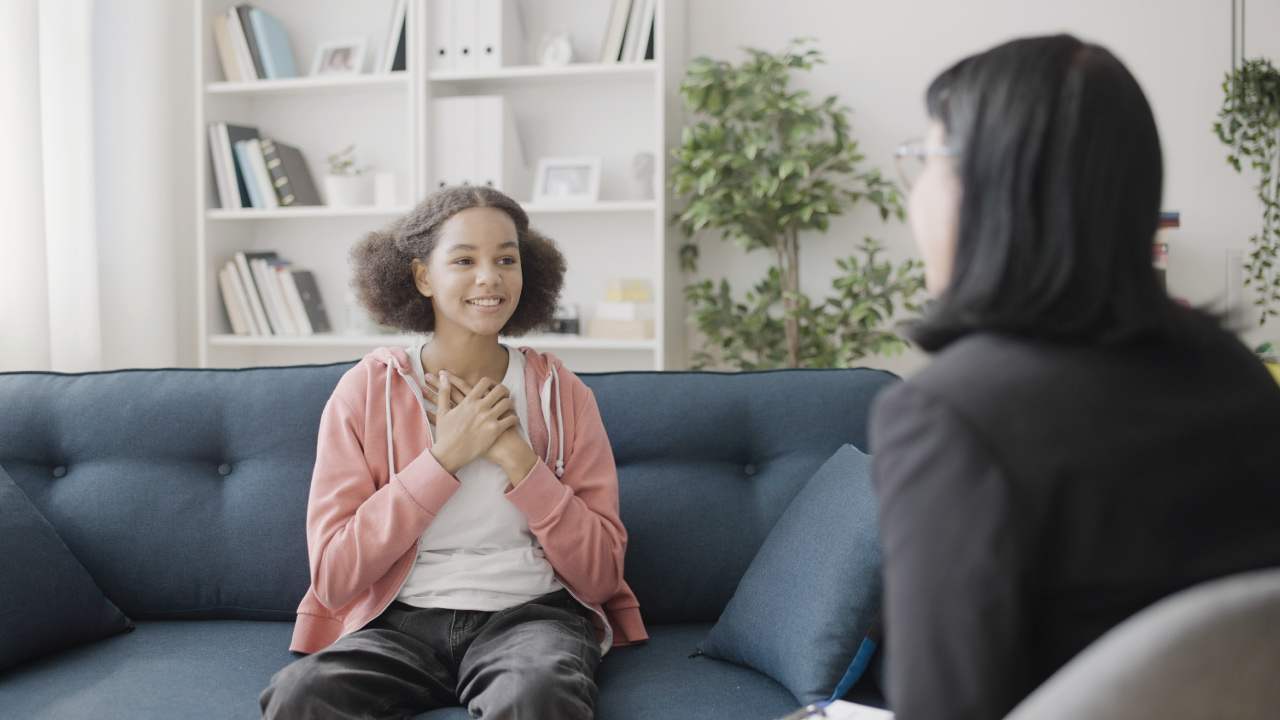 young girl sitting on couch talking with care coach